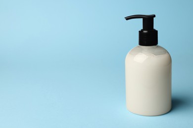 Photo of Bottle of liquid soap on light blue background, space for text
