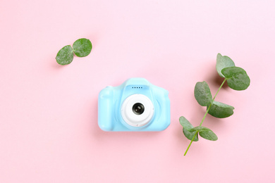 Photo of Toy camera and eucalyptus on pink background, top view