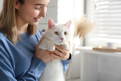 Photo of Young woman with her beautiful white cat at home. Fluffy pet