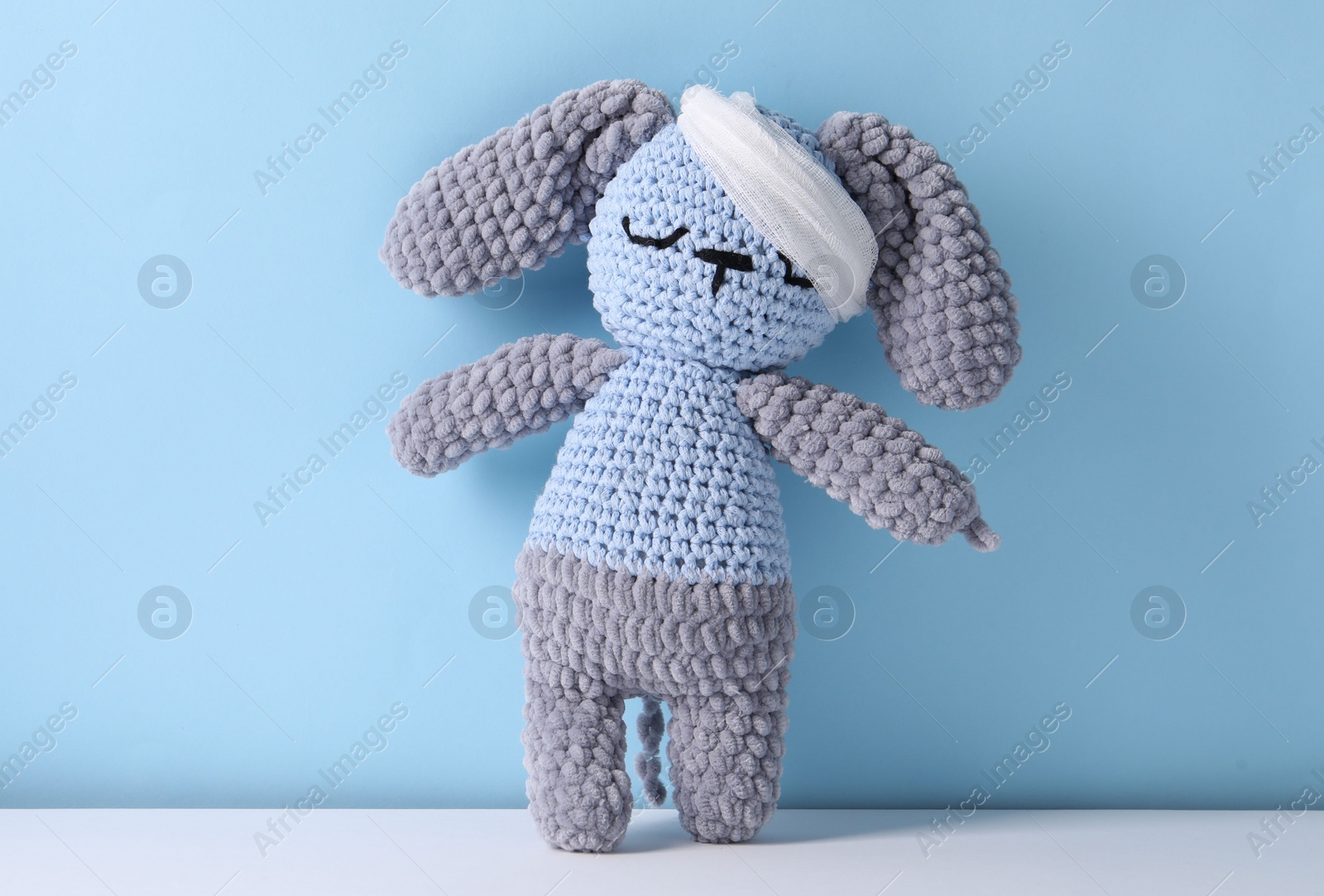 Photo of Toy bunny with bandage on color background