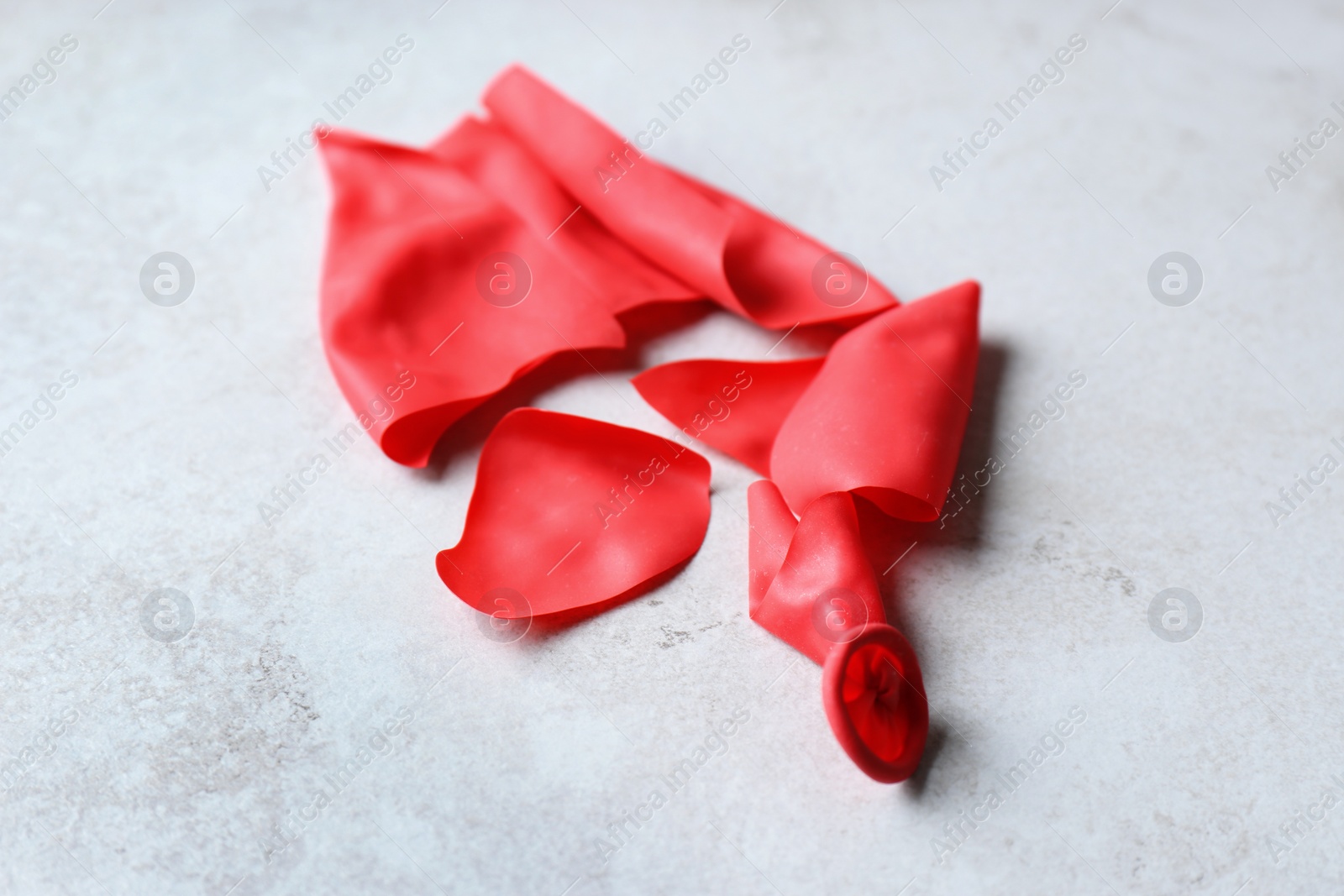 Photo of Popped red latex balloon on grey background