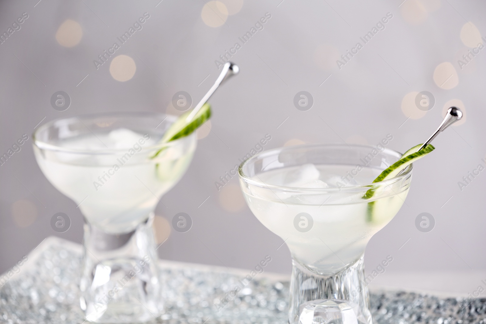 Photo of Glasses of martini with cucumber on tray against light background, closeup. Space for text