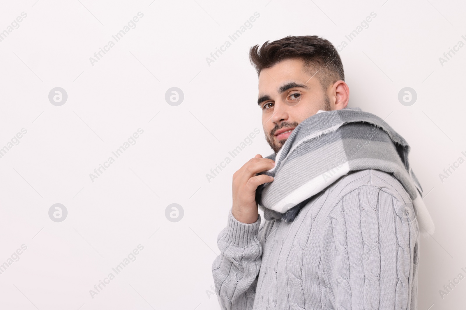 Photo of Portrait of smiling man in warm scarf on light background. Space for text