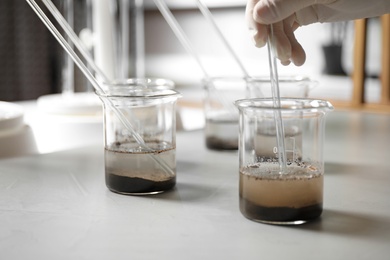 Scientist preparing soil extract at table, closeup. Laboratory analysis