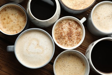 Many cups of different coffees on wooden table, flat lay