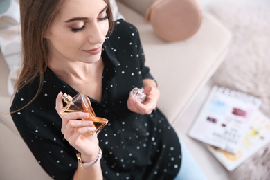 Photo of Beautiful young woman using perfume indoors, above view. Space for text