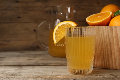 Many ripe oranges and fresh juice on wooden table. Space for text