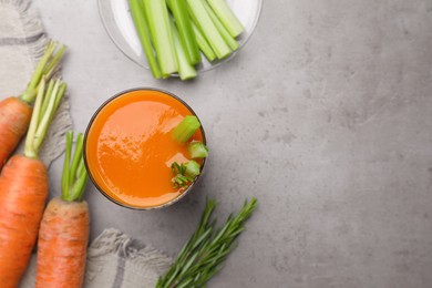 Photo of Glass of tasty carrot juice with celery sticks on grey table, flat lay. Space for text
