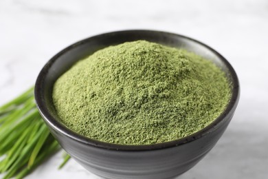 Photo of Wheat grass powder in bowl on white table, closeup