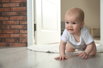 Photo of Cute little baby crawling on floor indoors, space for text