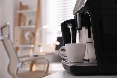 Photo of Modern coffee machine pouring milk into cup in office. Space for text