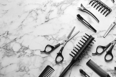 Flat lay composition with scissors and other hairdresser's accessories on white marble background. Space for text