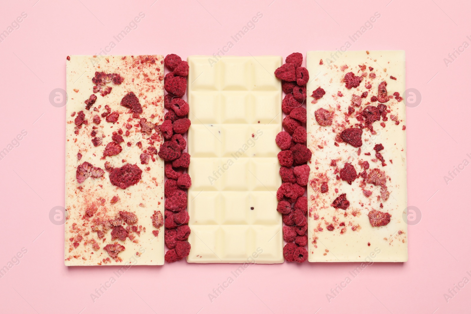 Photo of White chocolate bars with freeze dried fruits on pink background, flat lay