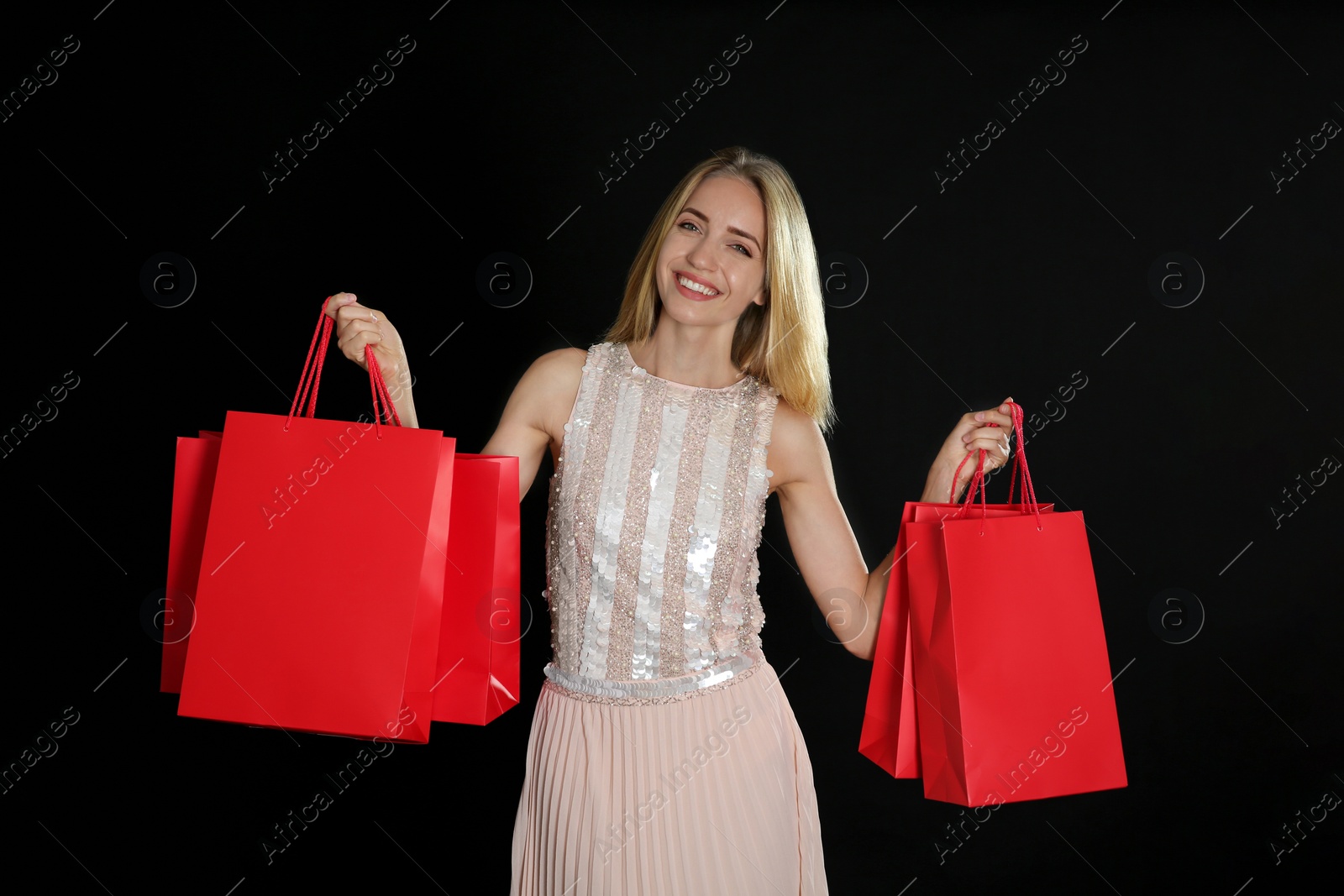 Photo of Happy young woman with shopping bags on dark background. Black Friday Sale