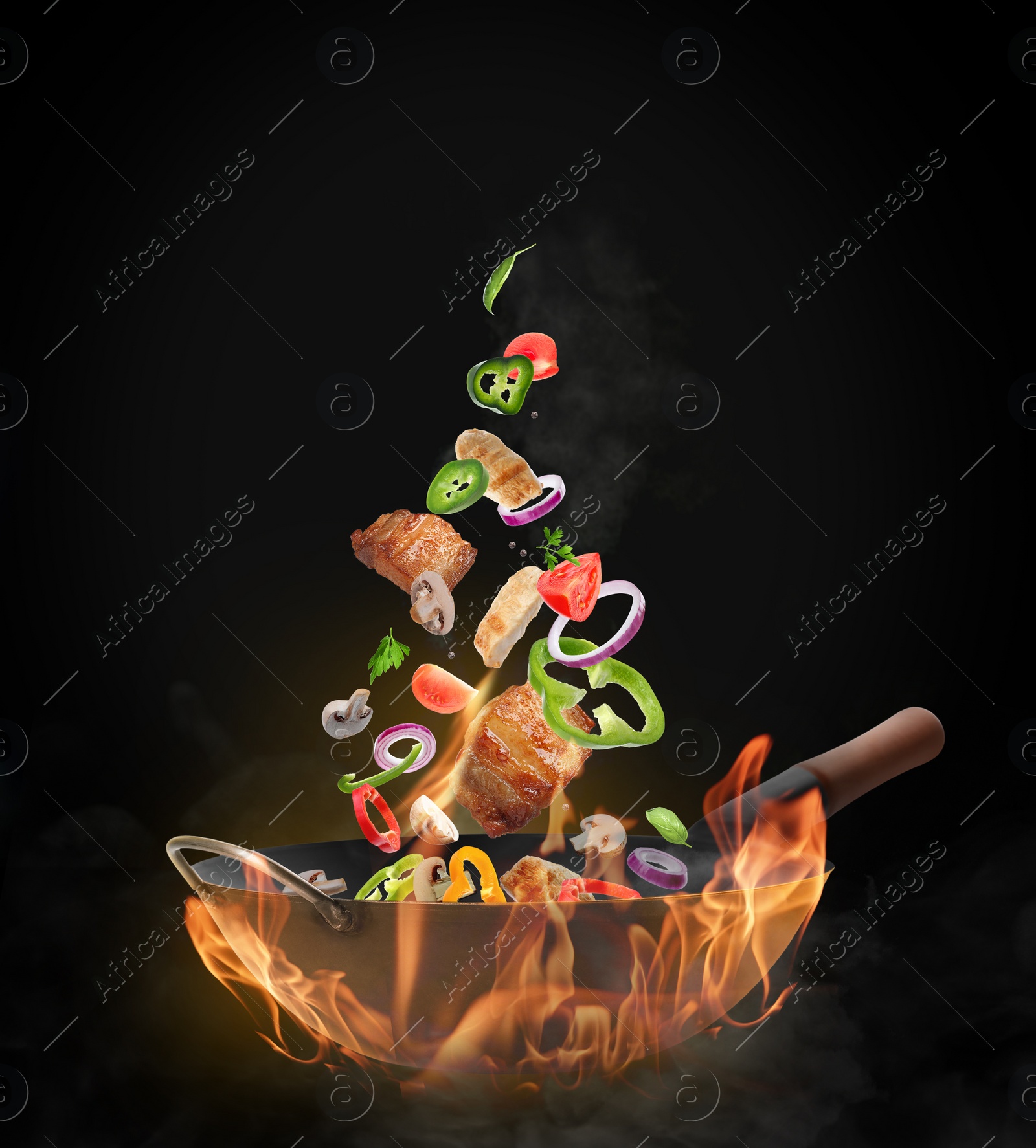 Image of Wok with tasty ingredients and fire on black background