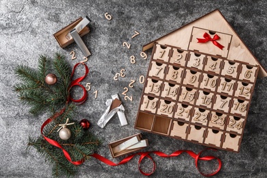 Photo of Flat lay composition with house shaped advent calendar and Christmas decor on grey background