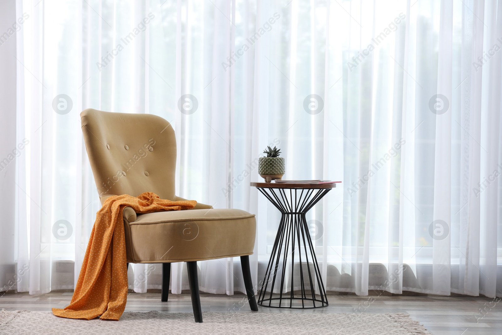 Photo of Comfortable armchair with clothes and beautiful plant near window indoors