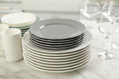 Clean plates, cups and glasses on white marble table in kitchen