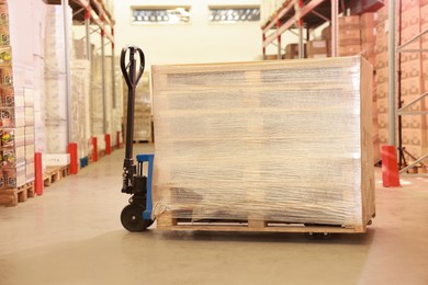 Wooden pallets wrapped in stretch on manual forklift indoors