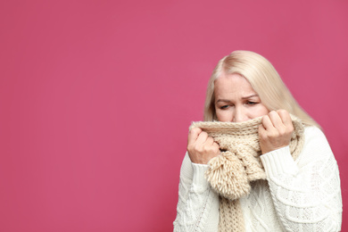 Image of Mature woman coughing on pink background, space for text. Cold symptoms