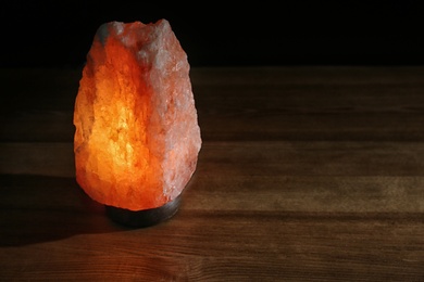 Photo of Himalayan salt lamp on wooden table. Space for text