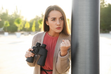 Photo of Jealous woman with binoculars spying on ex boyfriend outdoors