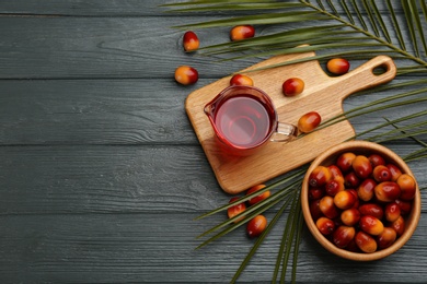 Photo of Flat lay composition with palm oil and fresh fruits on grey wooden table. Space for text