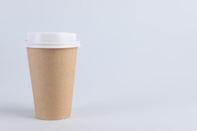 Photo of Paper cup with plastic lid on light background, space for text. Coffee to go