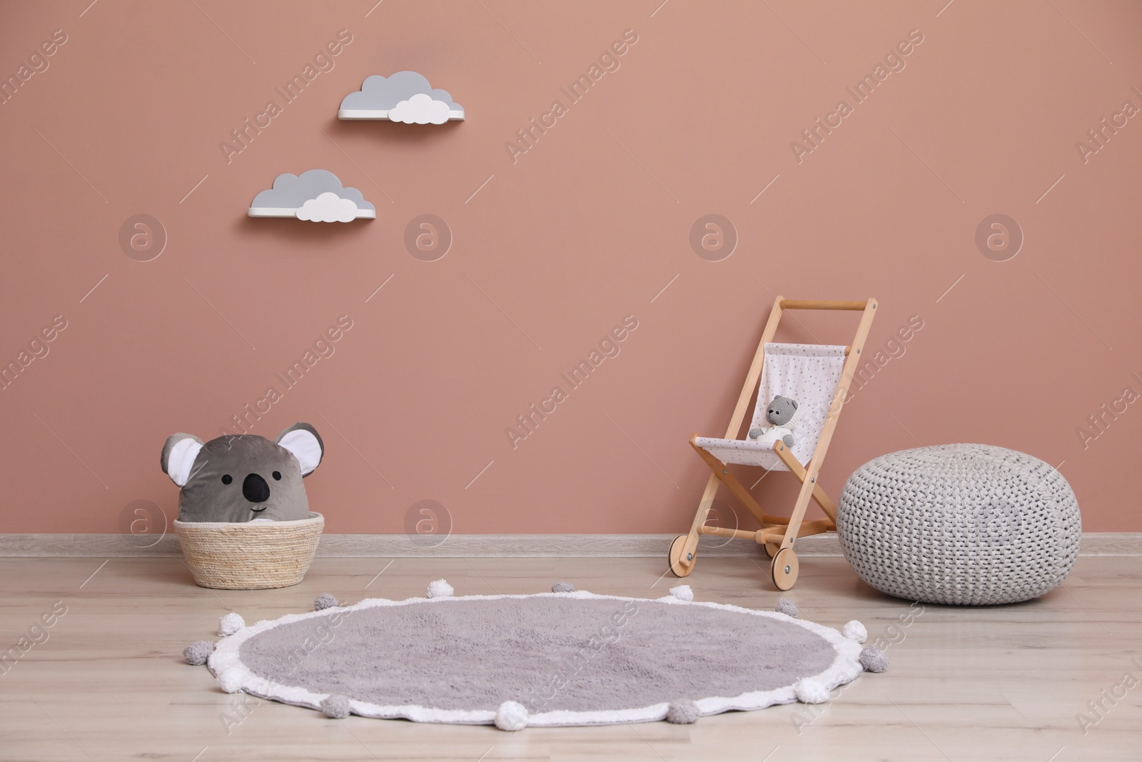 Photo of Wicker basket, toys and pouf near pink wall indoors. Interior design