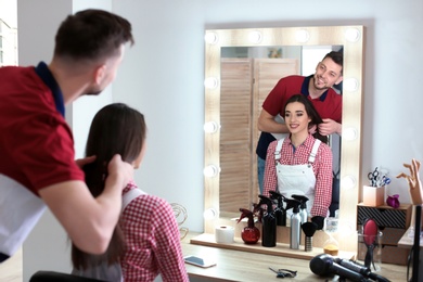 Photo of Professional hairdresser working with client in beauty salon