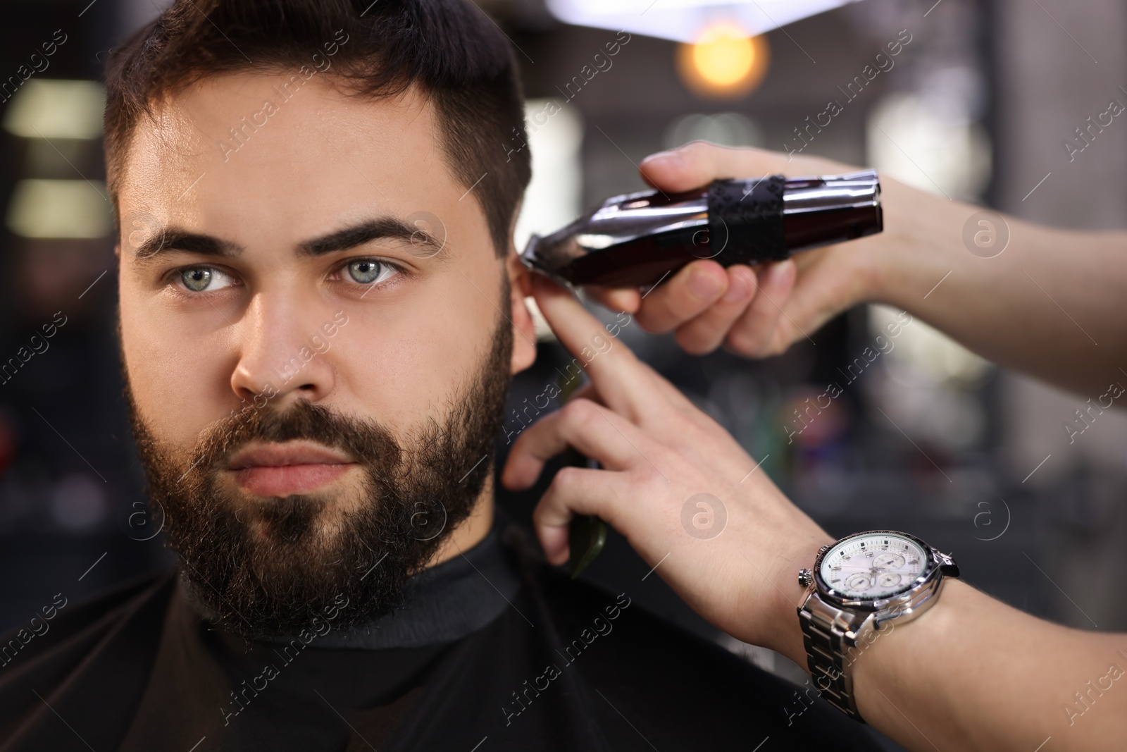 Photo of Professional hairdresser working with client in barbershop