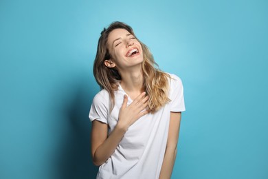 Photo of Cheerful young woman laughing on light blue background