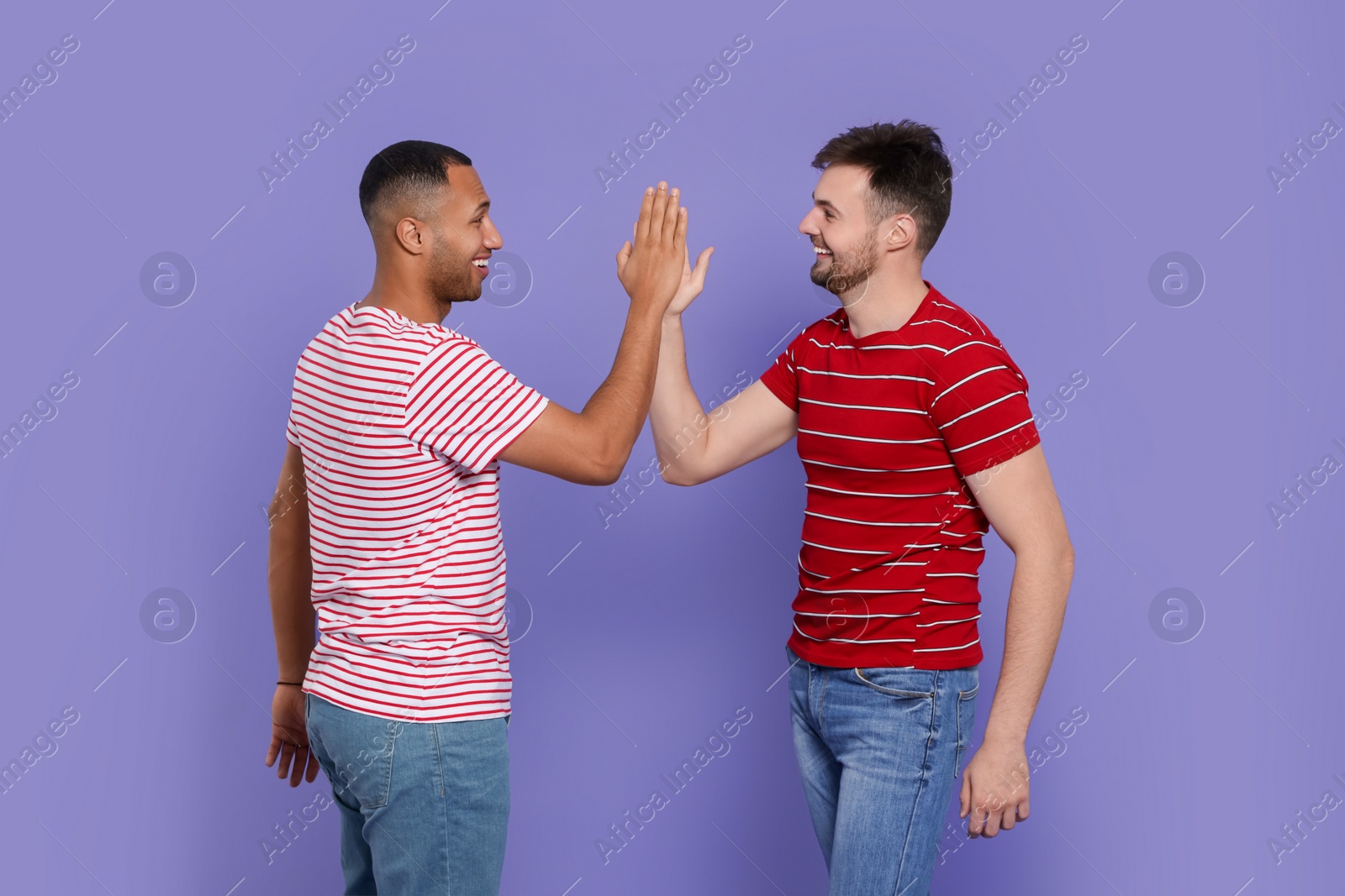 Photo of Men giving high five on purple background