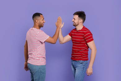 Men giving high five on purple background