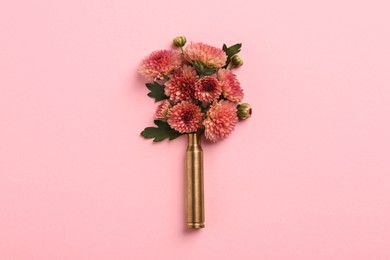 Photo of Beautiful flowers in bullet case on pink background, top view