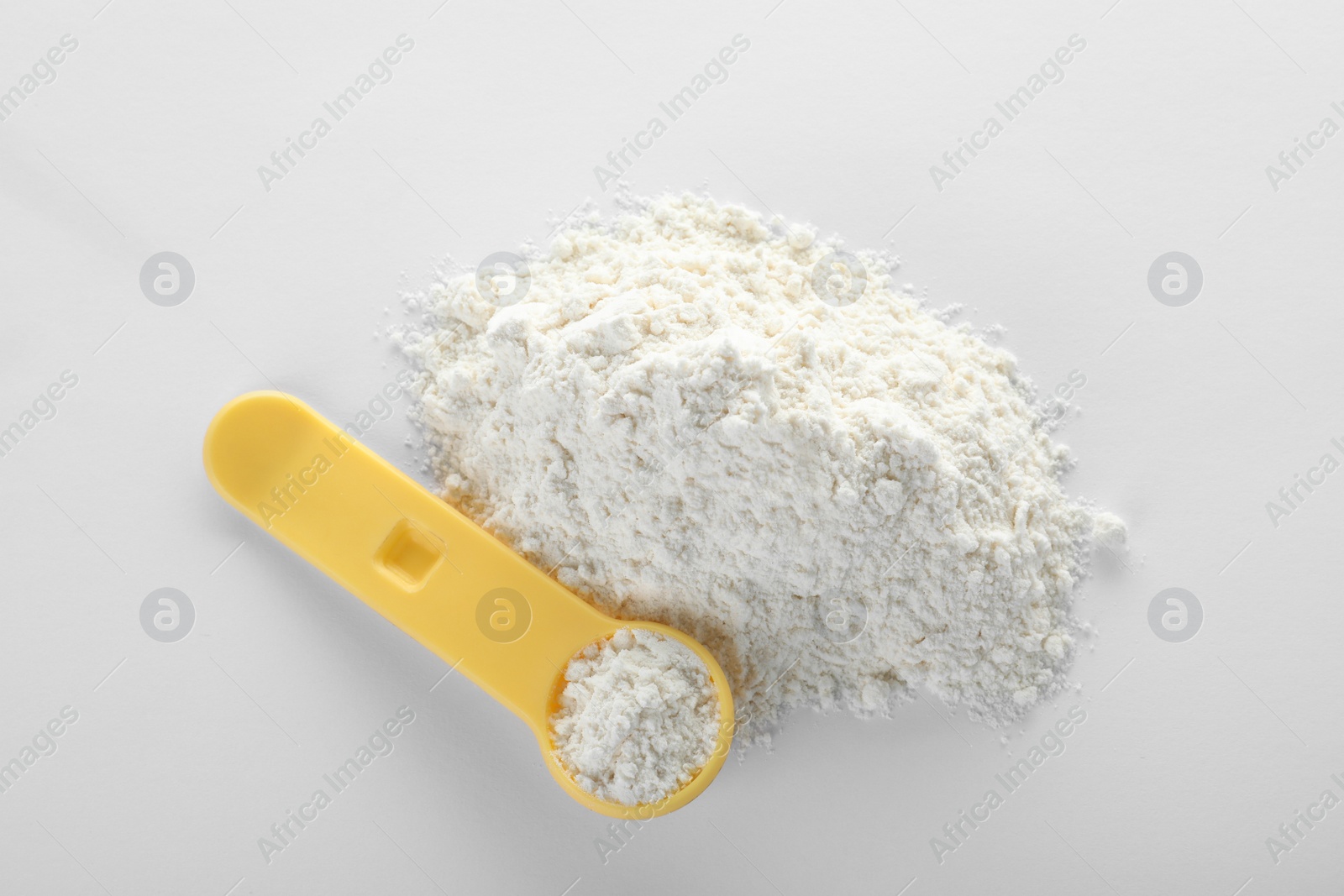 Photo of Spoon and pile of protein powder on white background, top view