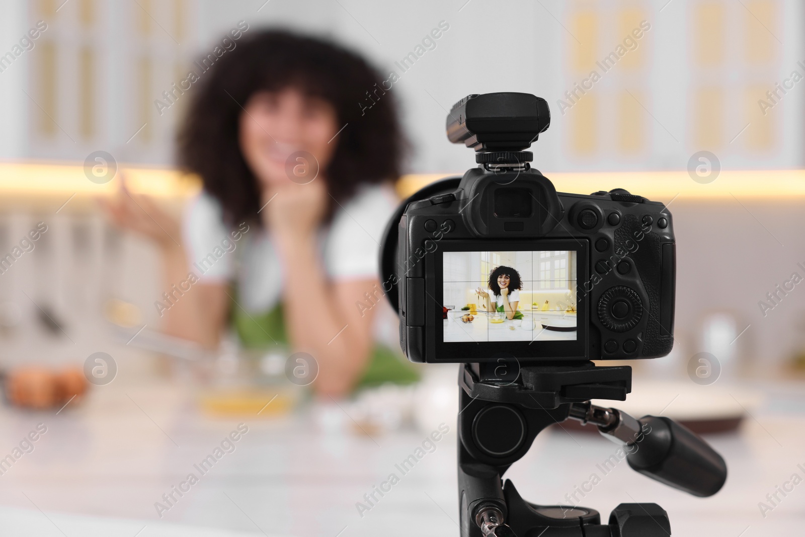 Photo of Food blogger recording video in kitchen, focus on camera