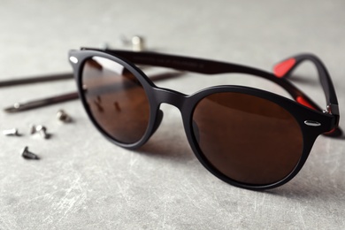 Photo of Stylish female sunglasses and fixing tools on grey table