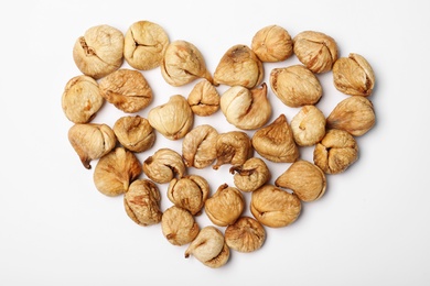 Photo of Heart shaped heap of dried figs on white background, top view. Healthy fruit