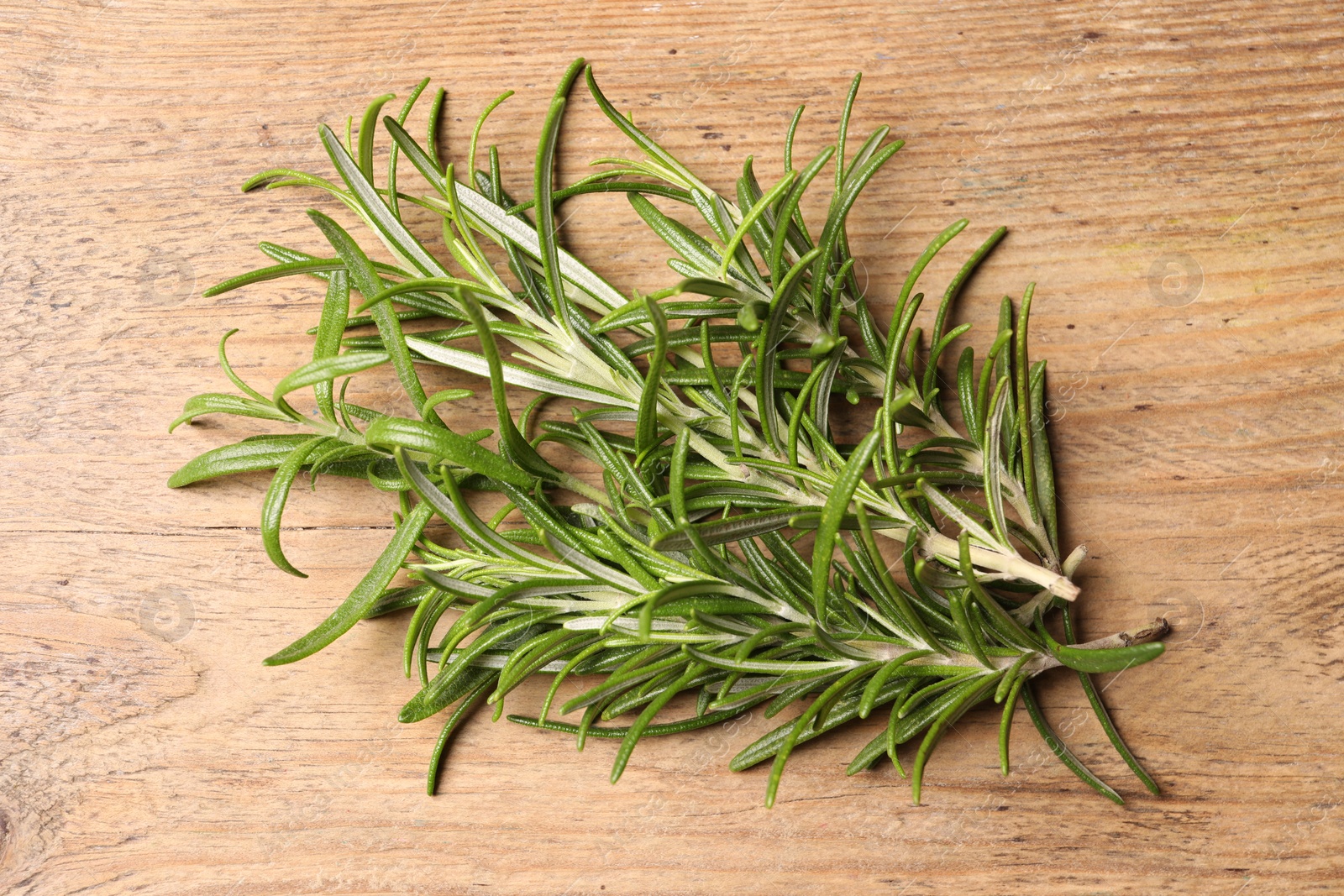 Photo of Fresh green rosemary on wooden table, top view