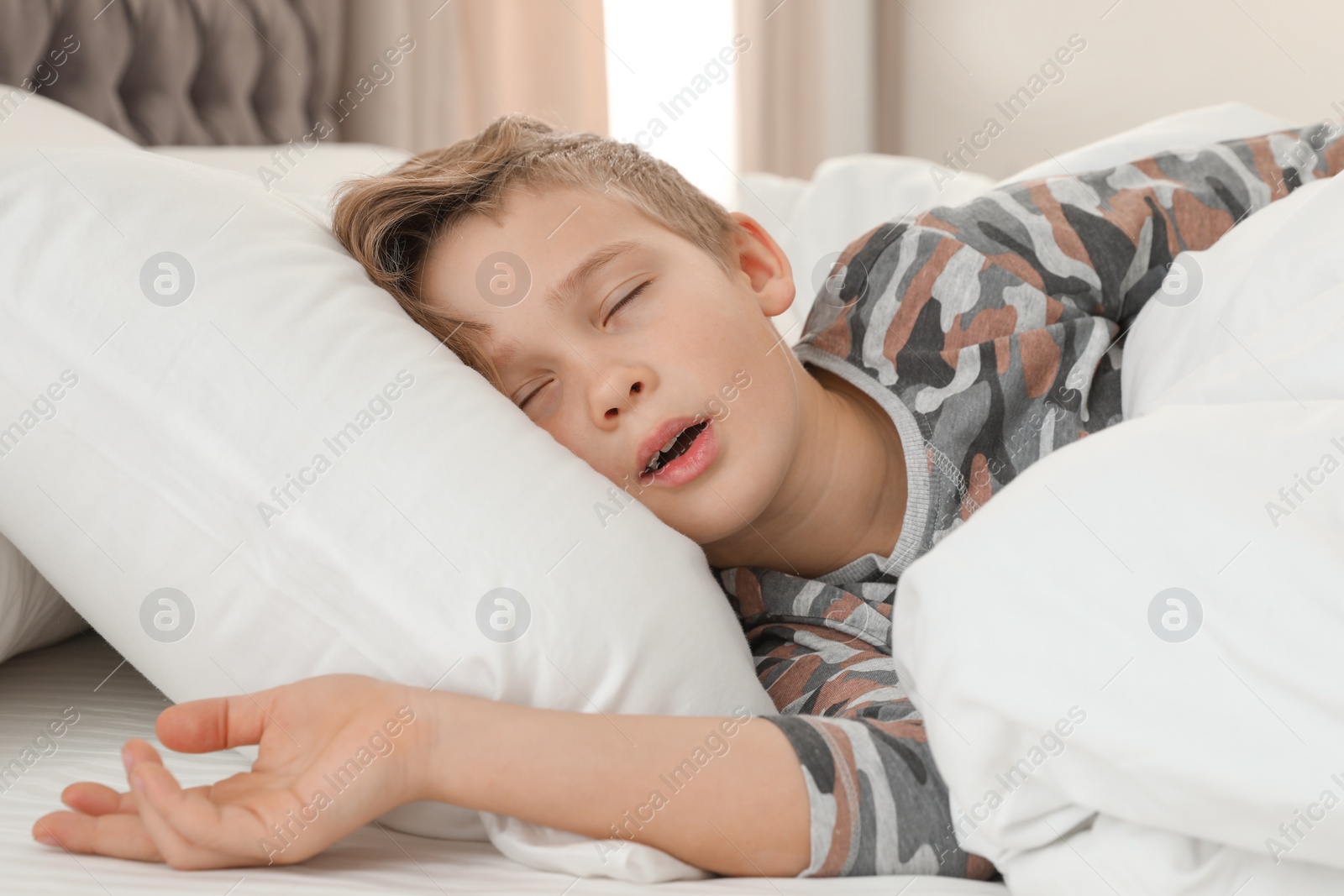 Photo of Cute tired boy sleeping in comfortable bed