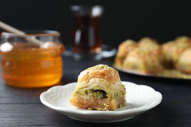 Photo of Delicious fresh baklava with chopped nuts on black wooden table, closeup. Eastern sweets