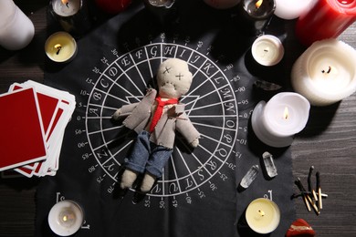Voodoo doll pierced with needle surrounded by ceremonial items on table, flat lay