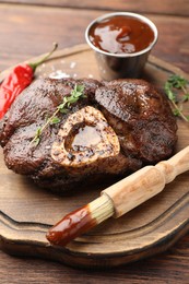 Photo of Delicious roasted beef meat served with sauce and spices on wooden table, closeup