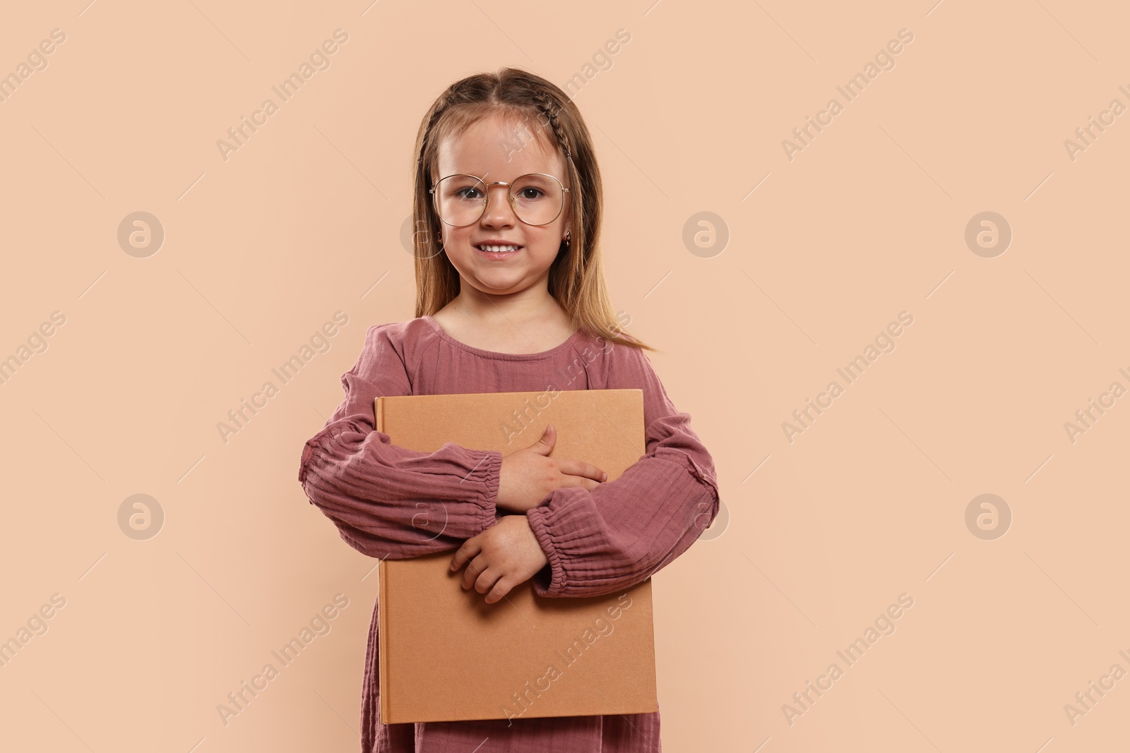 Photo of Cute little girl with book on beige background