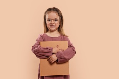 Cute little girl with book on beige background