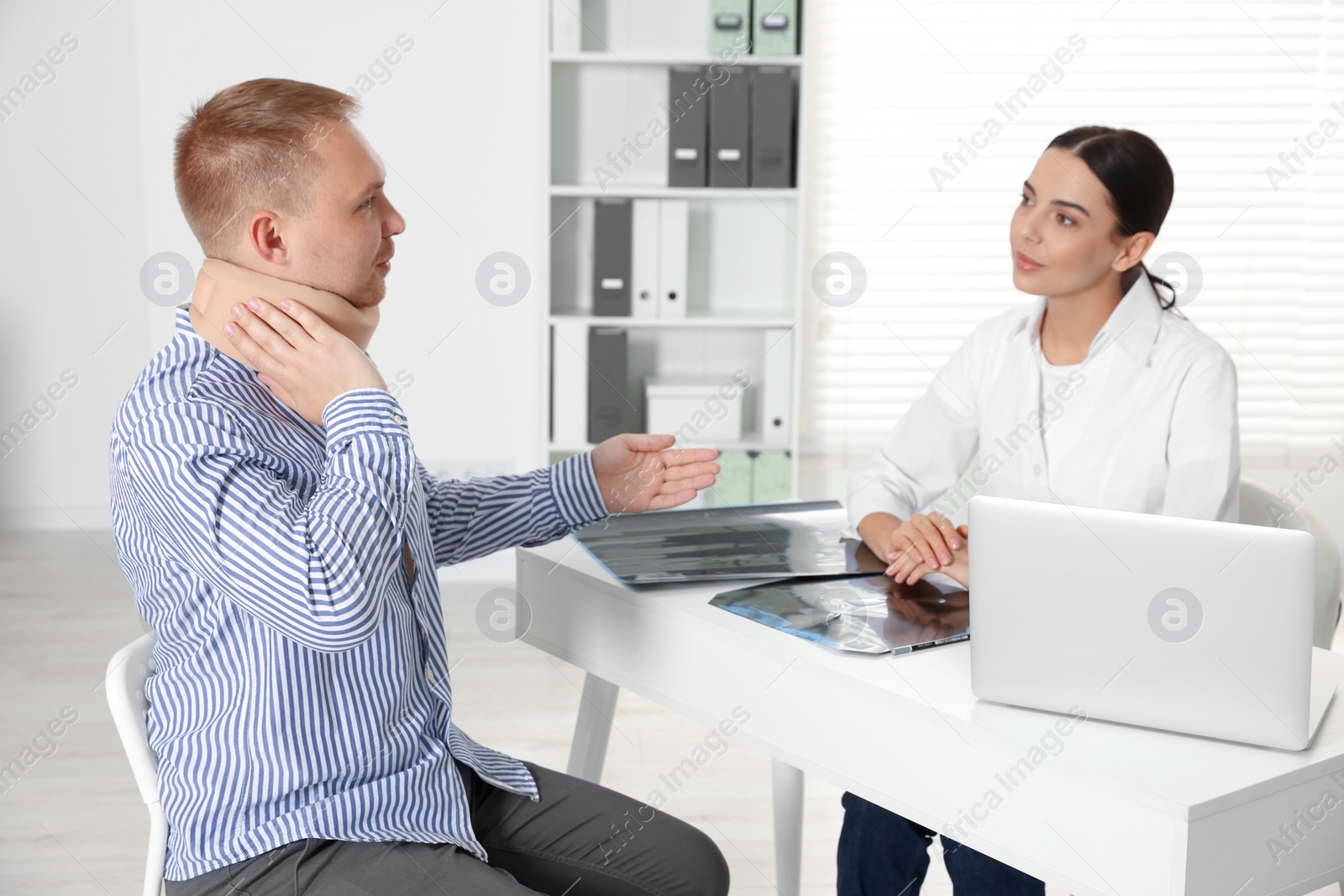 Photo of Doctor with neck MRI image consulting patient in clinic