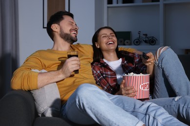 Photo of Couple watching comedy via TV and laughing at home in evening