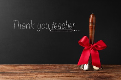 Image of School bell on wooden table near blackboard with phrase Thank You Teacher