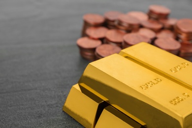 Photo of Stacked gold bars and coins on table, closeup. Space for text